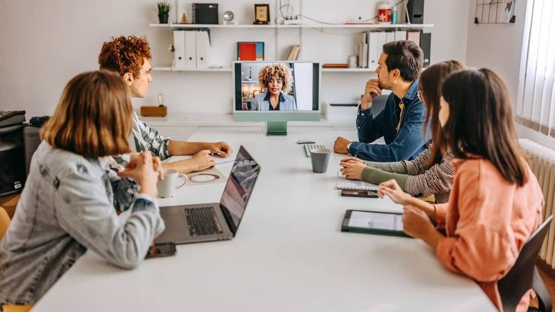 a team of five men and women in a conference call in the office